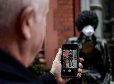 A passer by takes a a picture of the statue of Phil Lynott with a mask on as a result of the Coronavirus Epidemic 19/3/2020