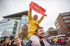 A young spectator holds a sign on her fathers shoulders 27/10/2024 