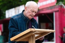 A supporter signs the book of condolence for Tommie Gorman before the game 28/6/2024