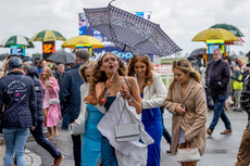 Racegoers shield themselves from the rain and wind at the Fairyhouse Easter Festival 10/4/2023
