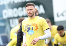 Andy Boyle warms up ahead of the game in a Darkness Into Light branded t-shirt 6/5/2024