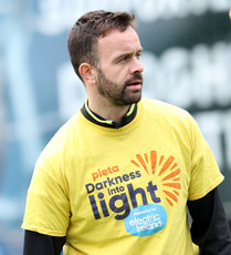 Robbie Benson warms up ahead of the game in a Darkness Into Light branded t-shirt 6/5/2024