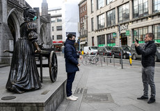 A passer by gets a picture with the Molly Malone statue with a mask on as a result of the Coronavirus Epidemic 19/3/2020